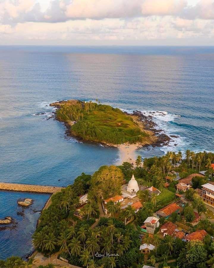 Surfers in the water waiting for waves in the beautiful Hiriketiya Bay